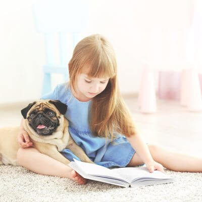 reading to dogs helps kids with autism, young girl reading to small pug