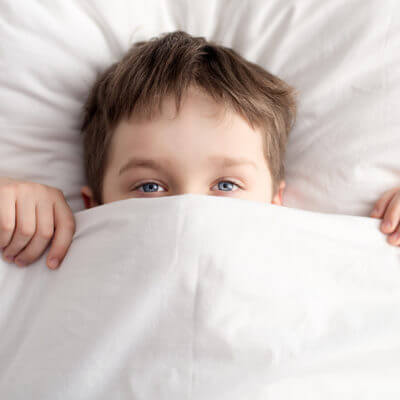 Little Boy In Bed Covering His Face With White Blanket Sleep disorders autism