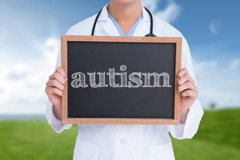 The word autism and doctor showing little blackboard against field and sky. Adult autism diagnosis