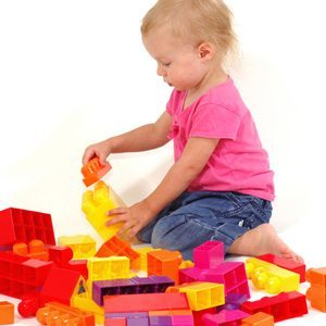 Young autistic girl playing with coloured plastic blocks